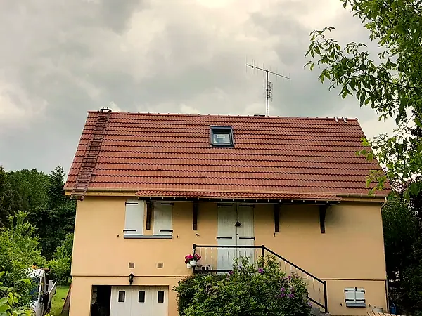 La même maison, sa toiture refaite en tuiles neuves avec une fenêtre de toit