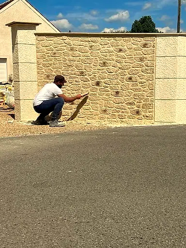 Maçon au travail devant un mur en pierre